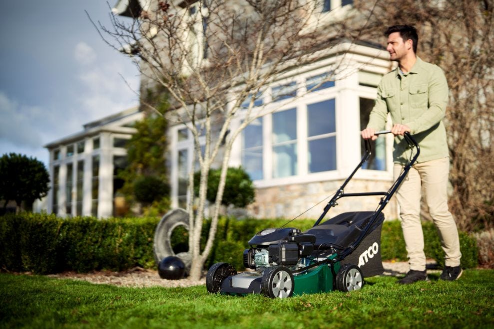 Man mowing lawn in autumn garden